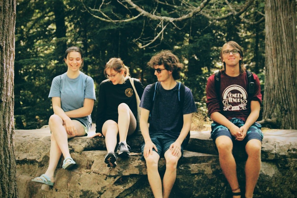 A group of young people sitting together on rocks in the woods