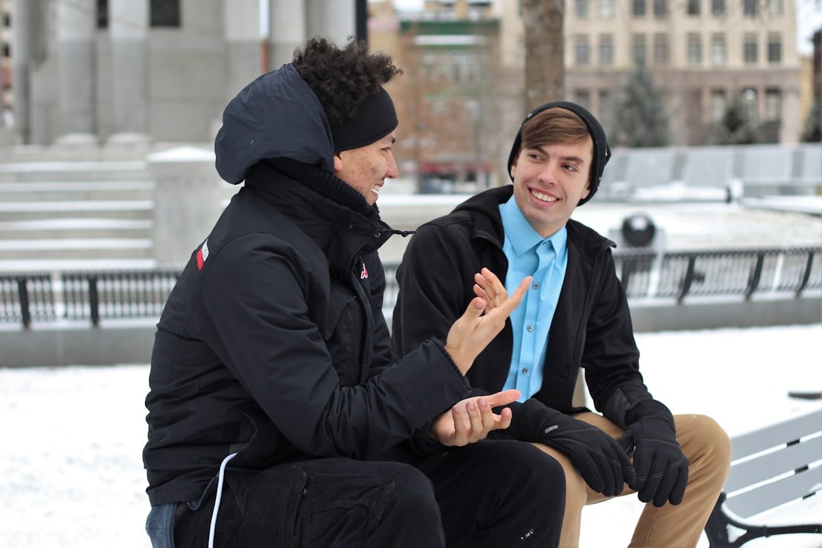 A mentor and a young person sitting together outdoors, talking one-to-one