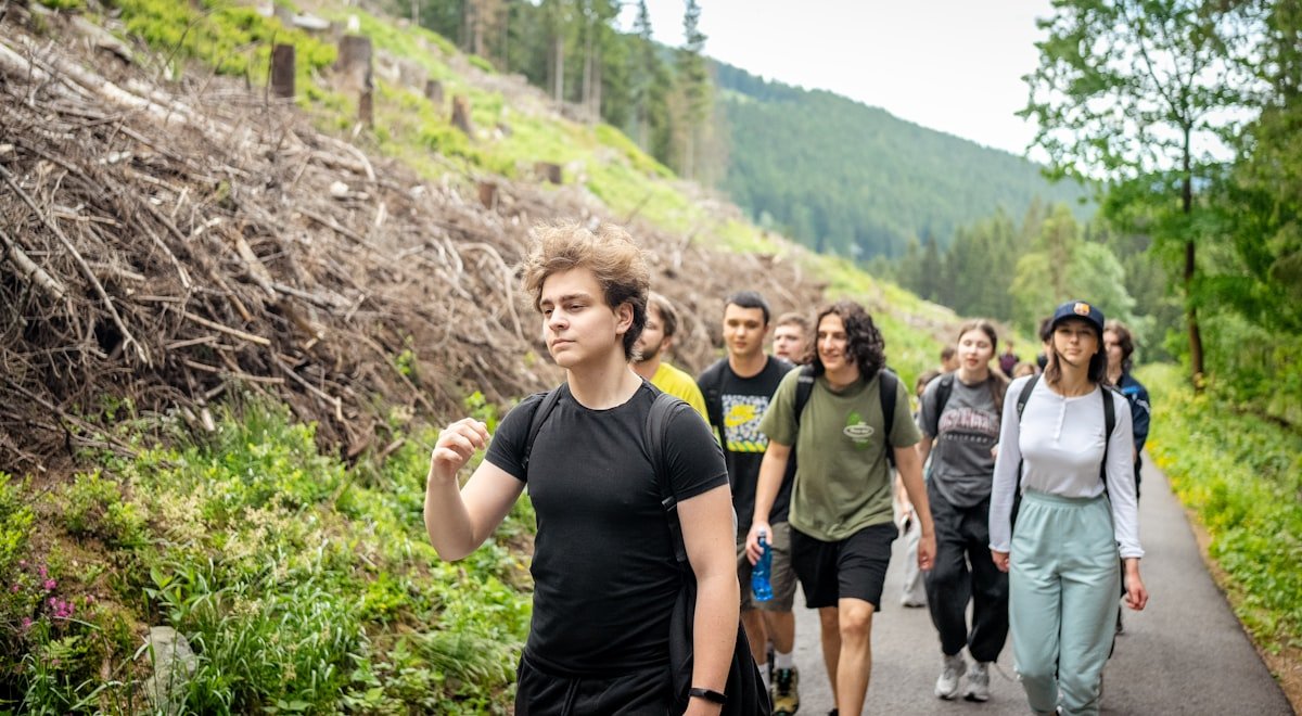 A group of young people hiking together on a forest trail during an outing